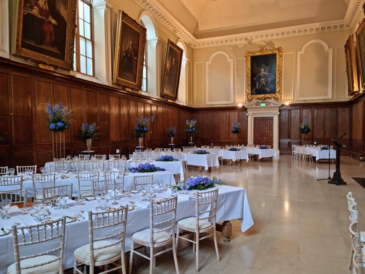 Fancy dinner set up in the dining hall with white chairs and white table cloths