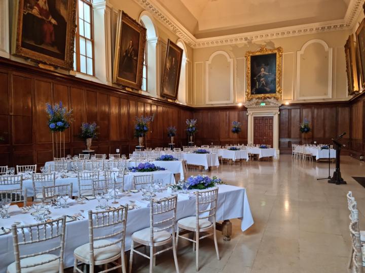 Fancy dinner set up in the dining hall with white chairs and white table cloths