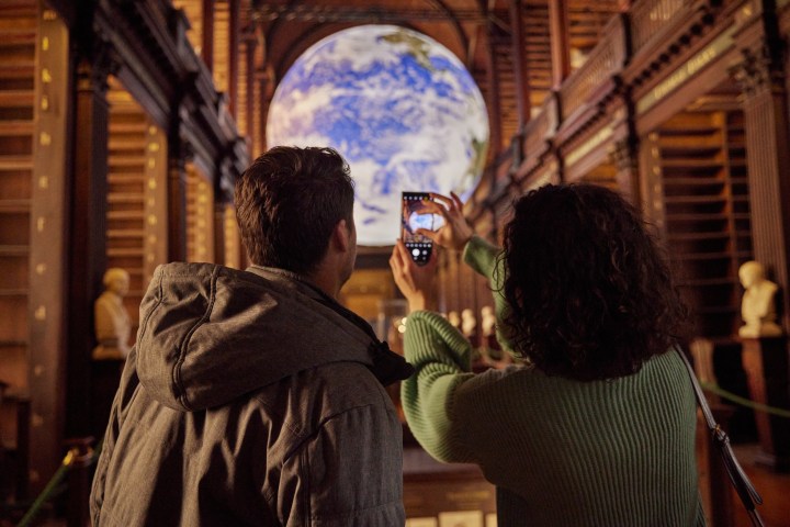 A couple taking a photograph of Gaia in the Long Room