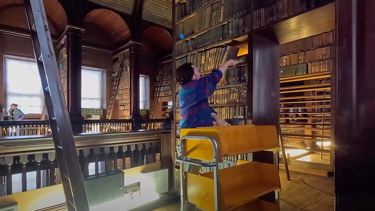 person adding books to an old shelf carefully