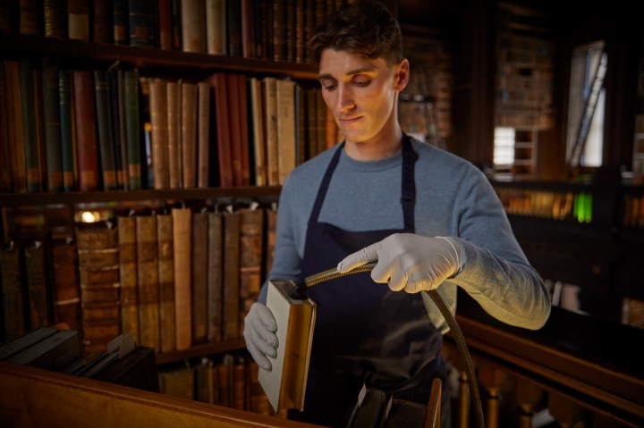 a man cleaning a book in the old library