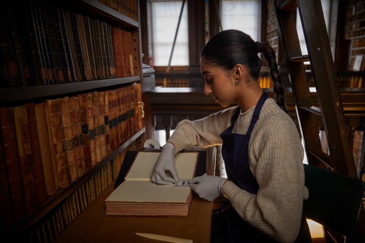 A woman adding images to a book in the old library
