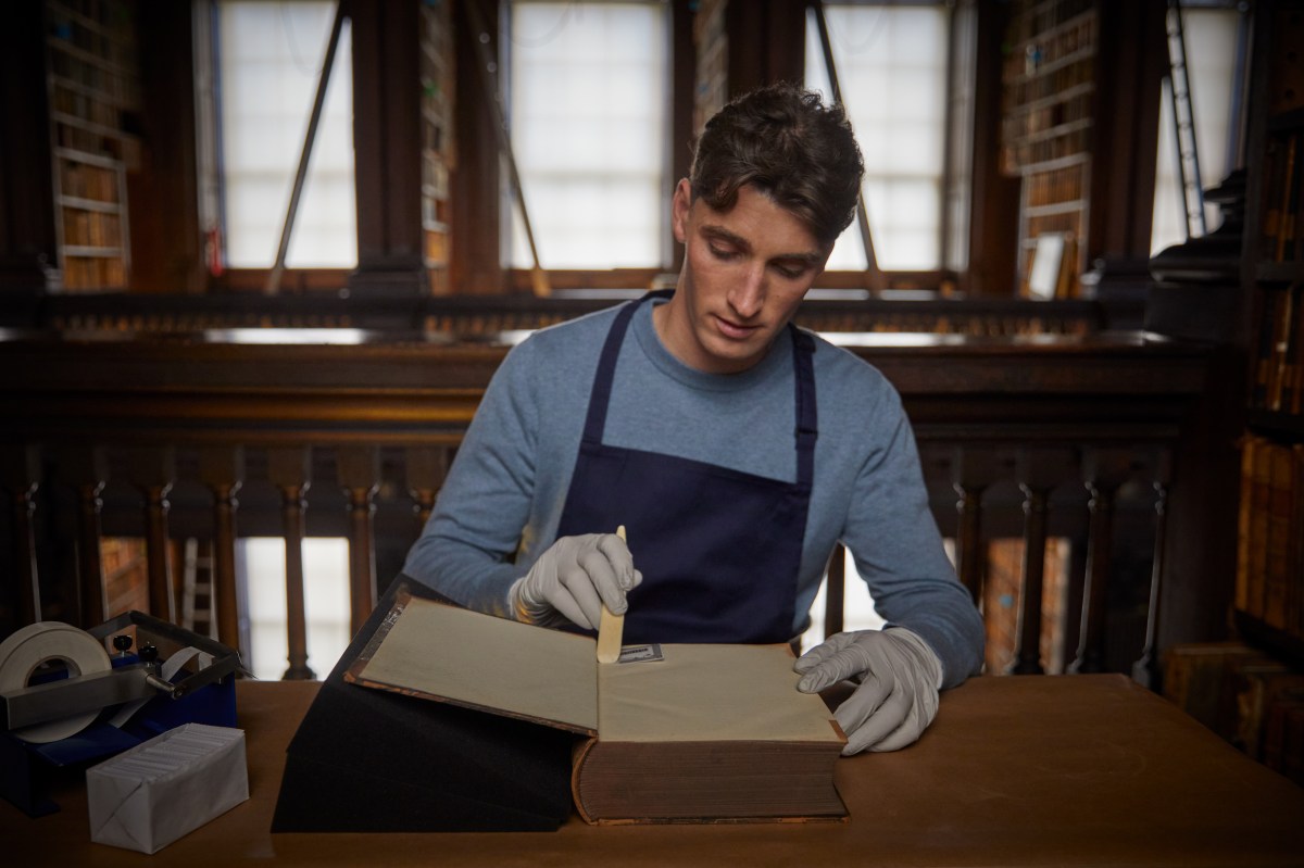 a man adding images into a book in the old library