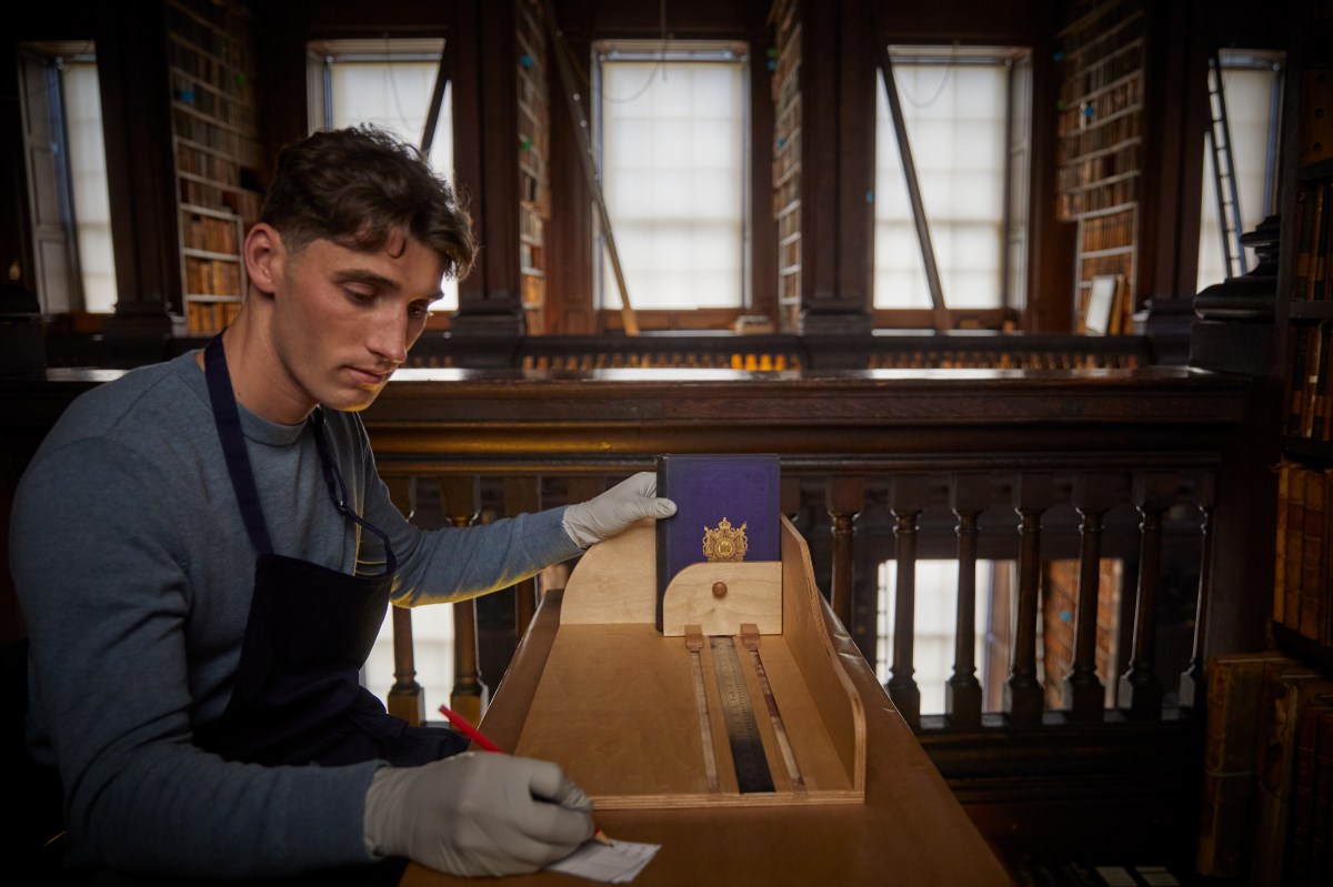 a man measuring a book in the old library