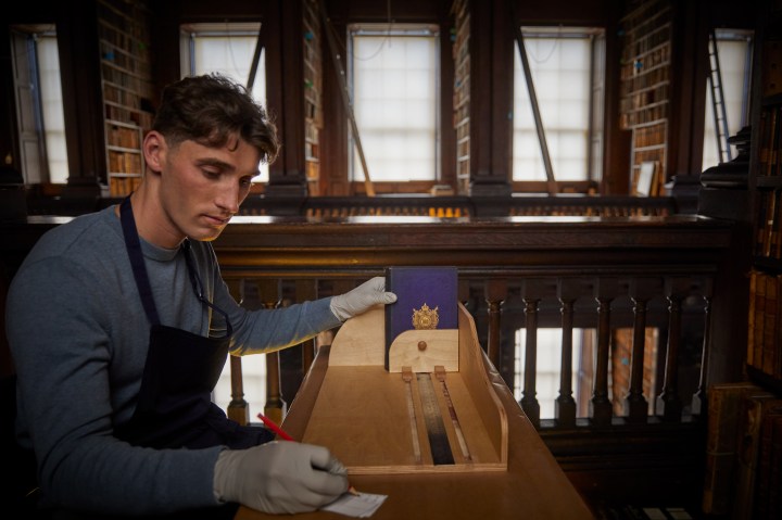 a man measuring a book in the old library
