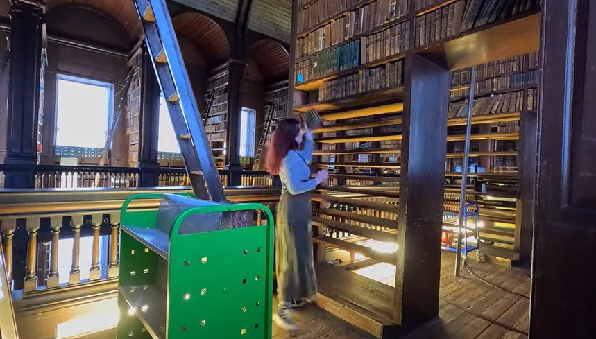 A woman putting books into empty bookshelves in the old library