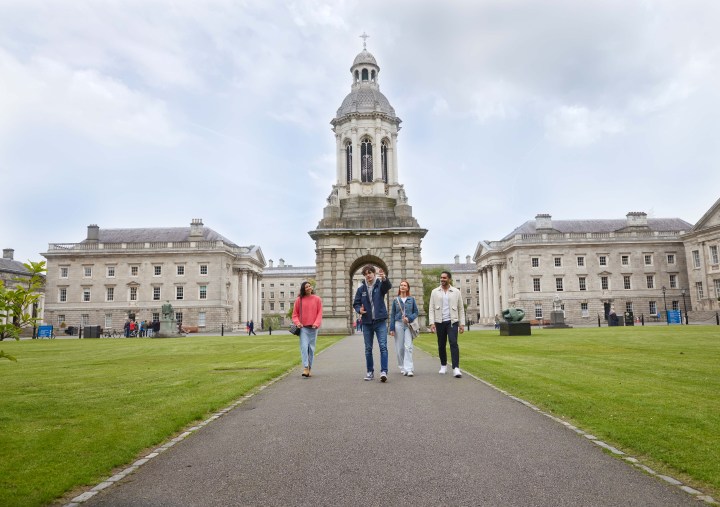 A Trinity guide with three tourists walking through Front Square during the historical walking tour of Trinity College.