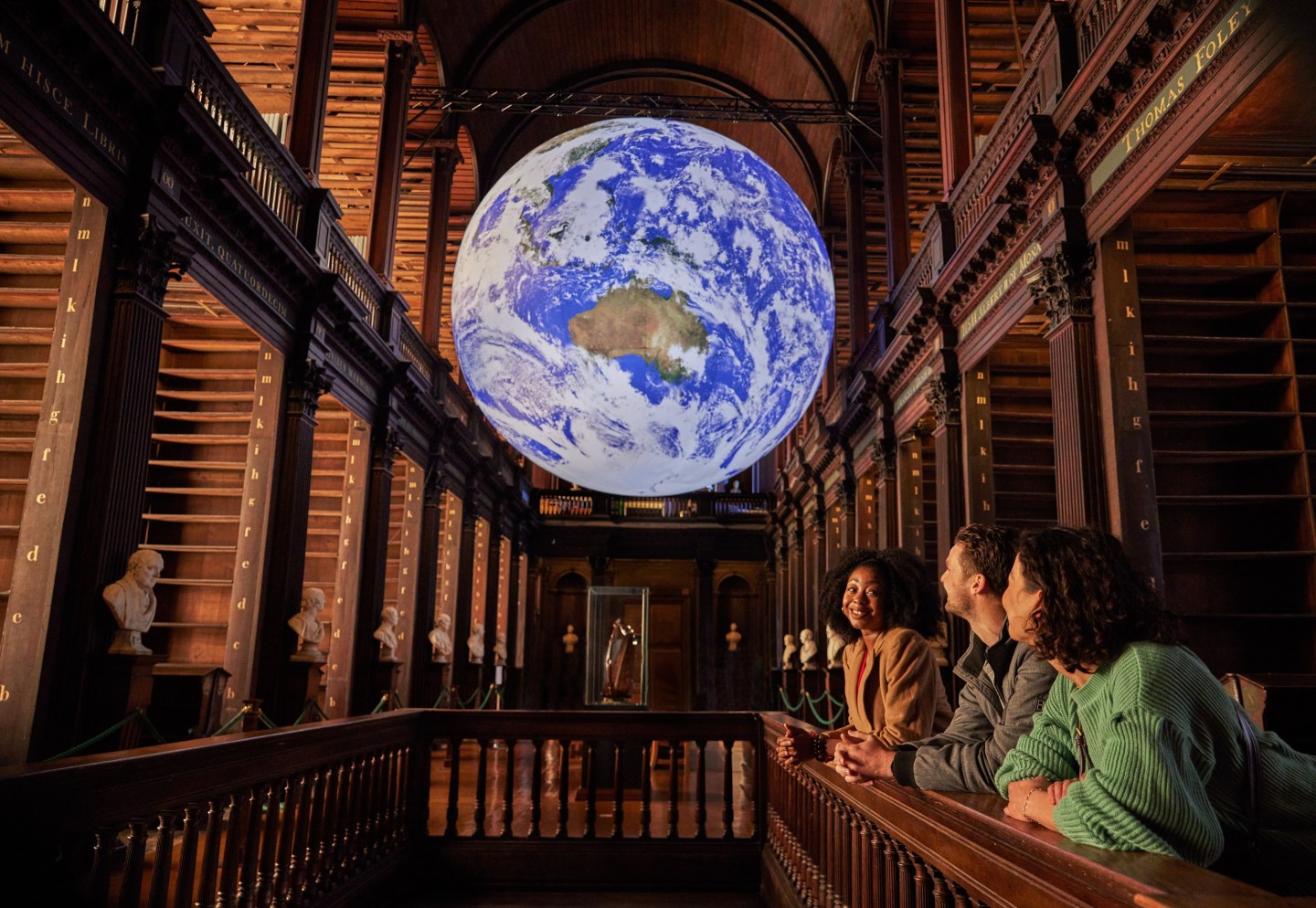 Three people looking at Gaia in the Long Room