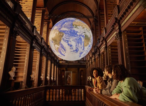 Three people looking at Gaia in the Long Room