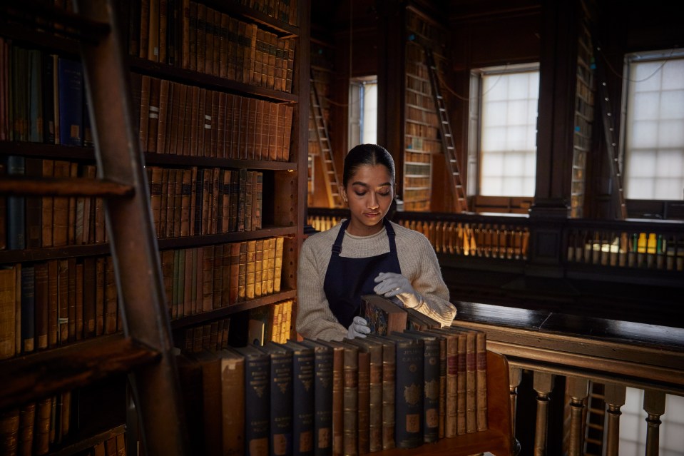An assistant moves a book on to a trolley at the Old Library.