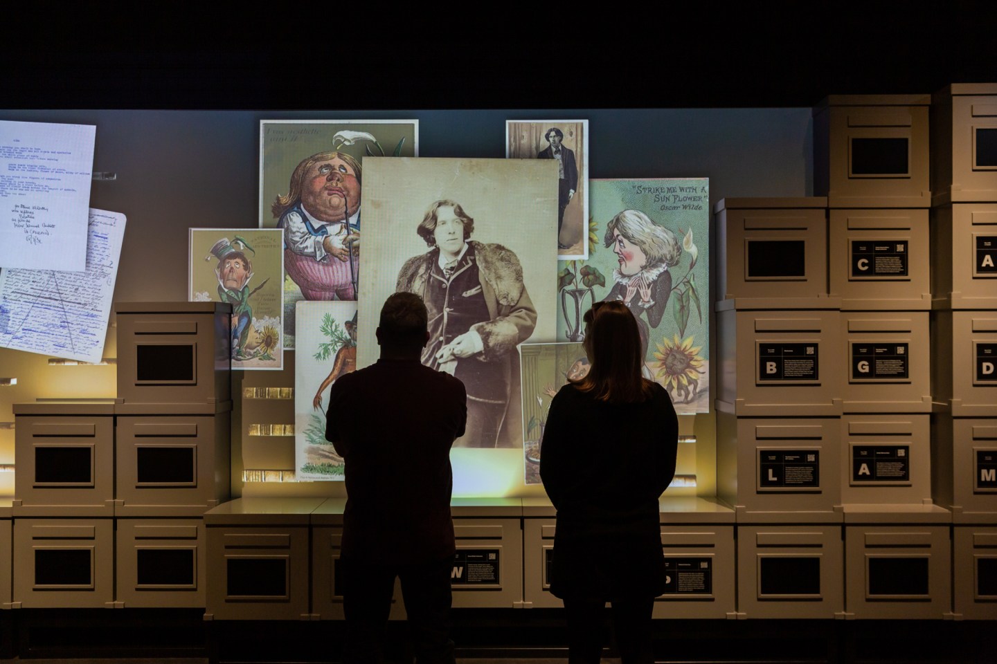 Two people looking at a display of Oscar Wilde and others