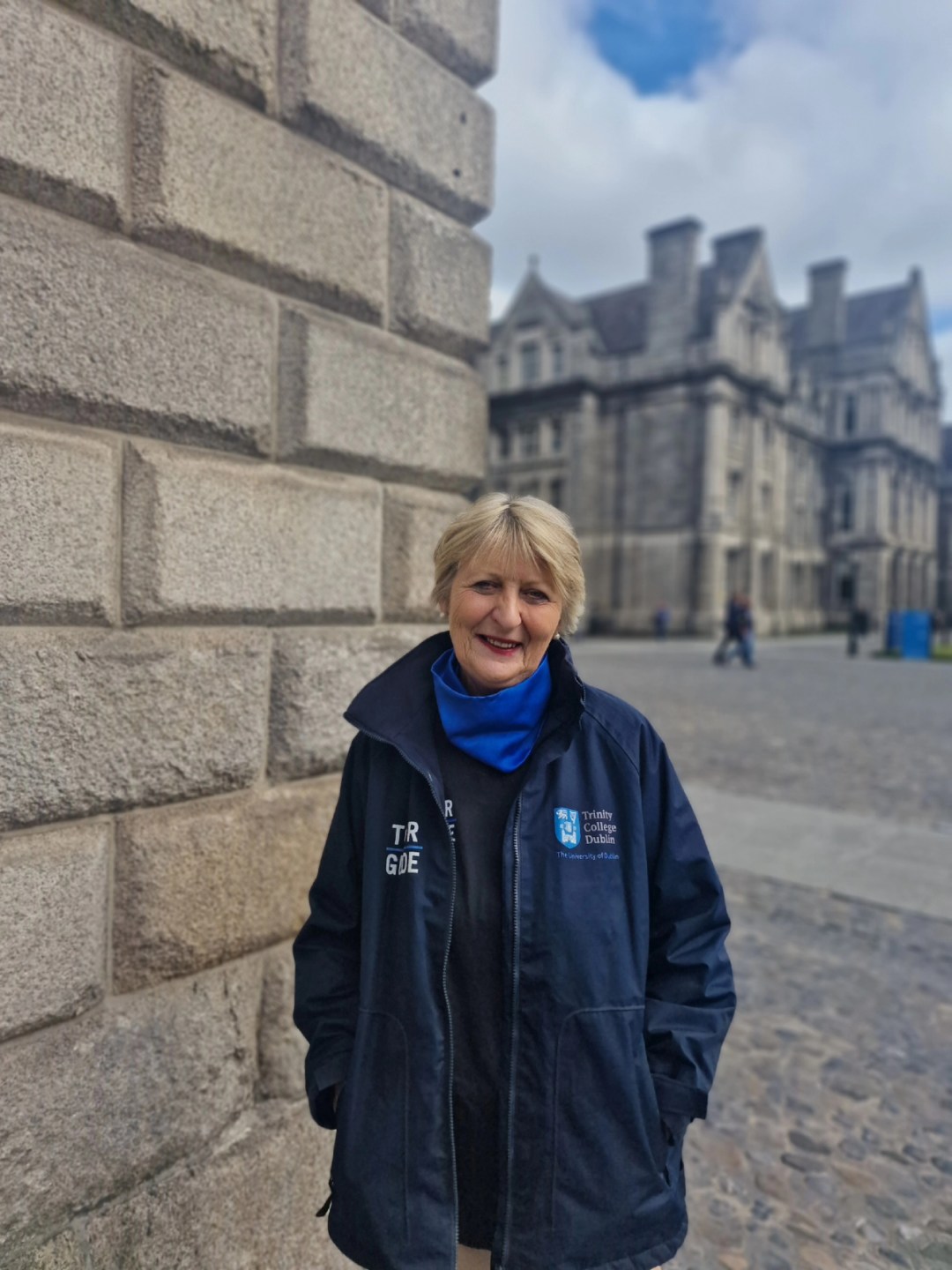Tour guide Anne wearing a navy tour guide jacket on Trinity campus