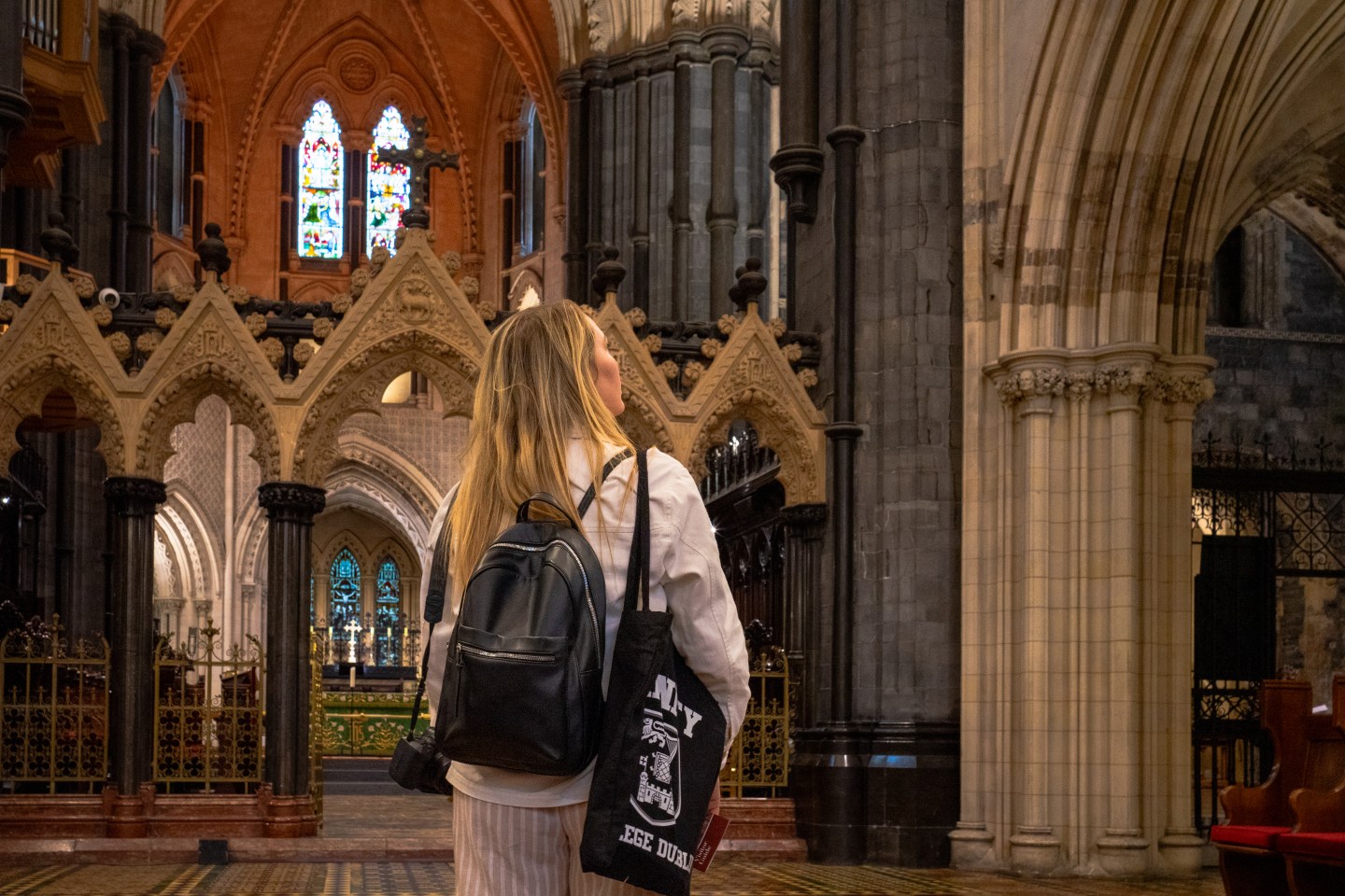 A woman inside Christ Church, admiring the stain-glass windows and artwork