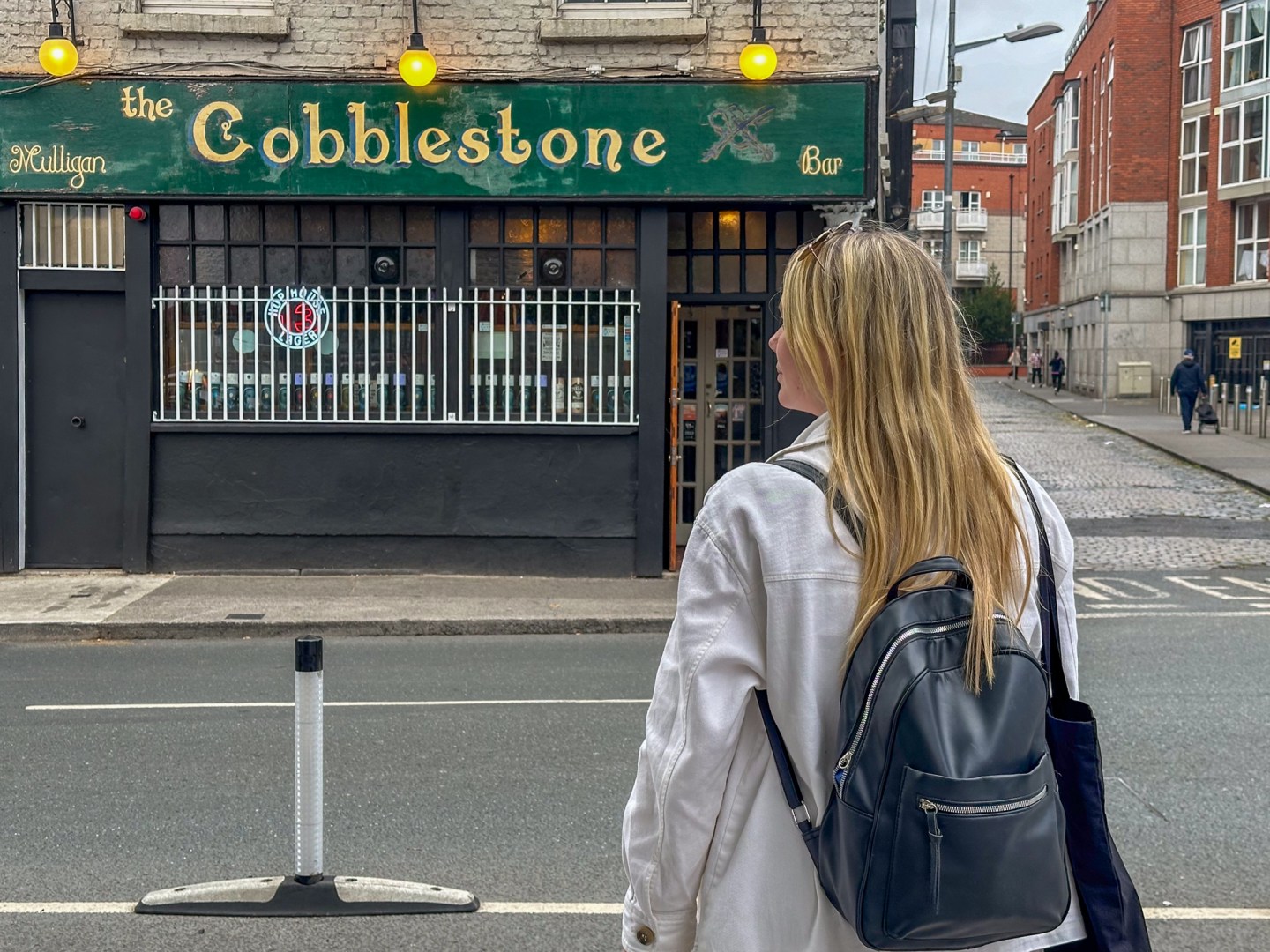 A woman crosses the street to the Cobblestone bar