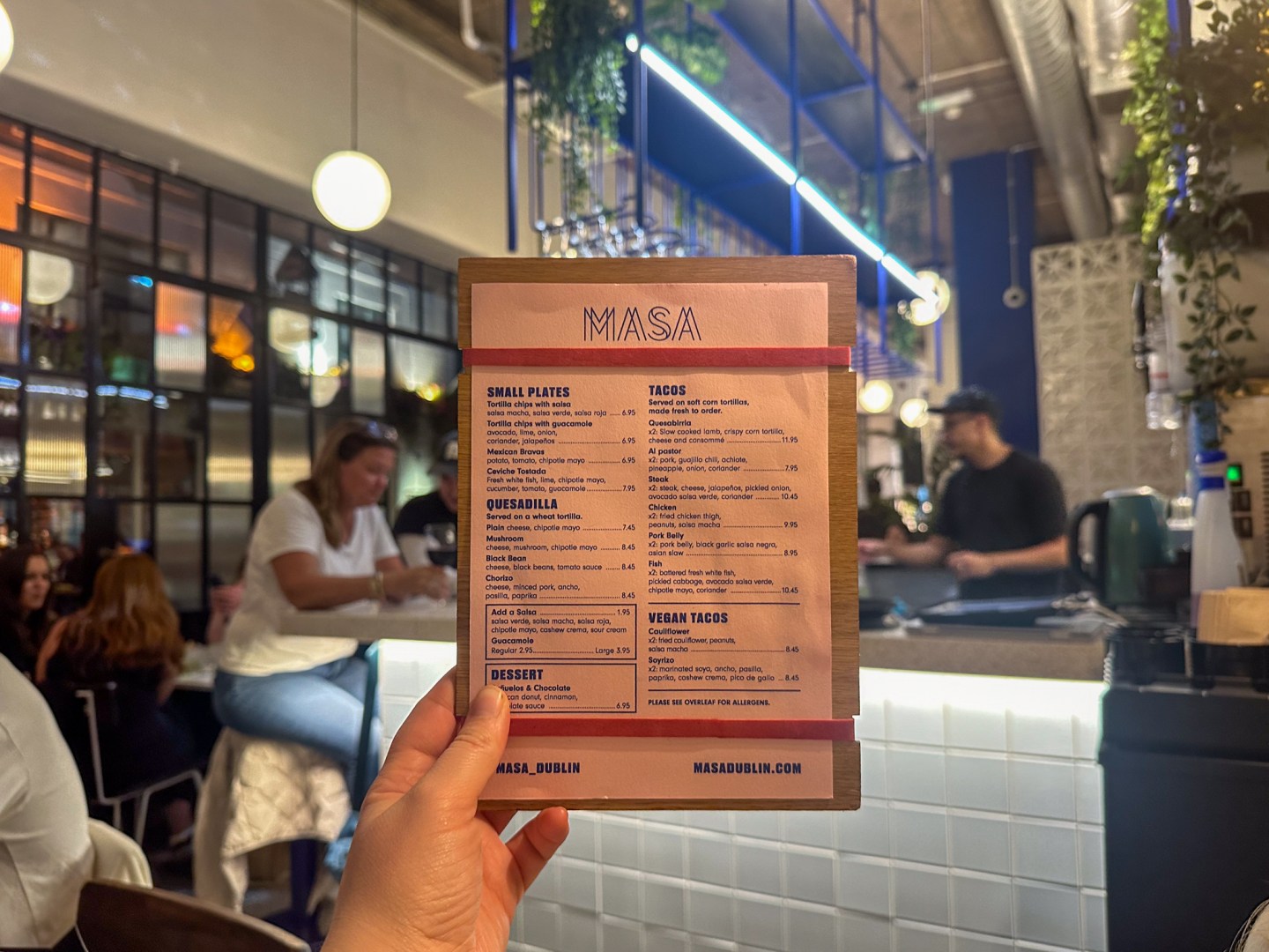 A hand holding up a menu of Mexican restaurant Masa