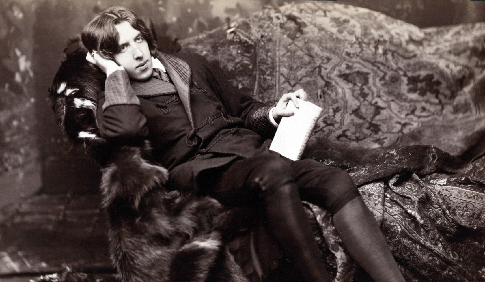 Black and white image of Oscar Wilde reclining on a couch