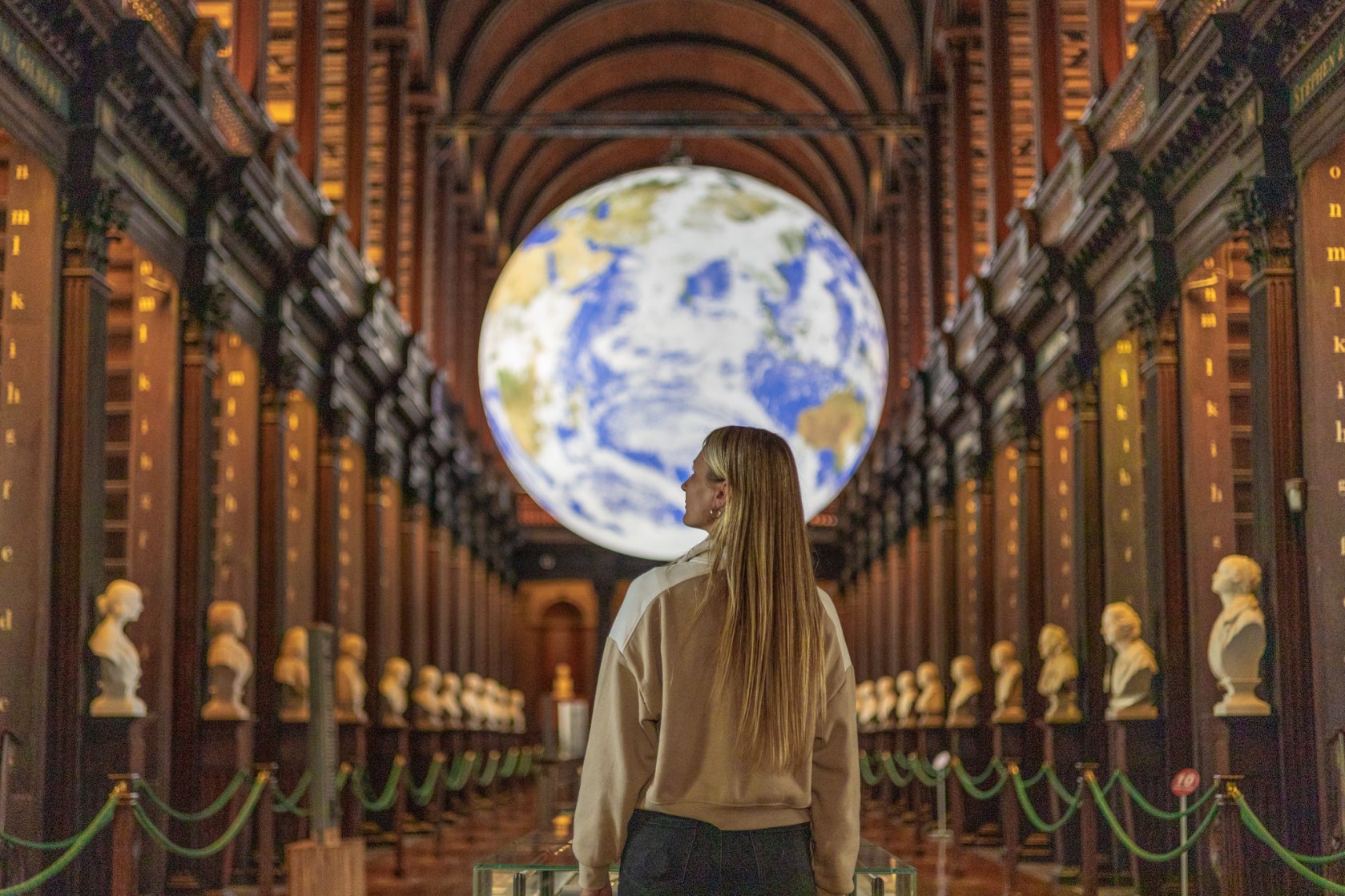 Image of a woman standing in front of the Gaia display, admiring the surroundings in the Long Room