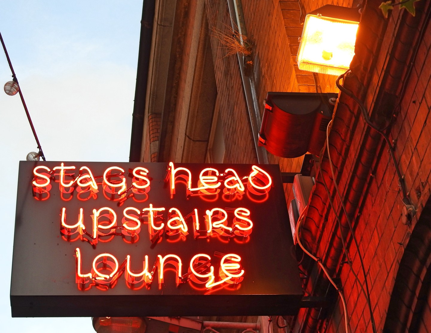 Picture of a sign that reads "Stags Head upstairs lounge" in red LED
