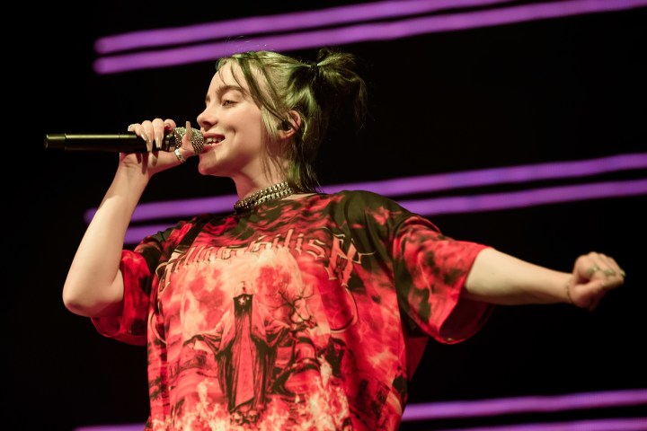 Billie Eilish holding a microphone and performing on stage