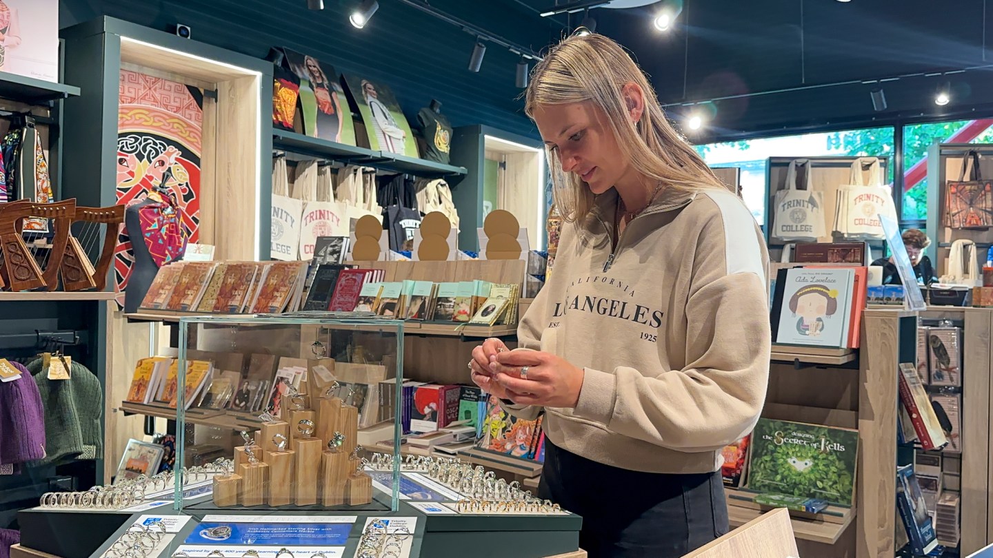 A women admires and tries on jewellery in the Trinity College gift shop