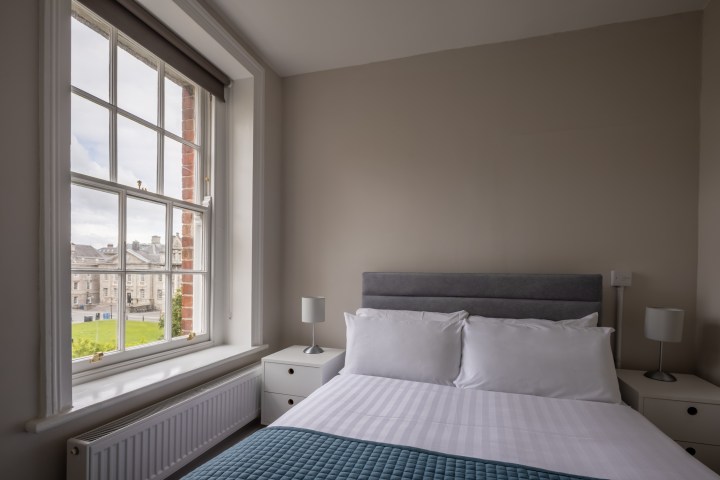 Double bed with a view of historic buildings in Trinity's front square